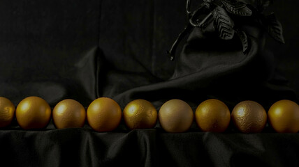 A luxurious minimalist scene with identical golden eggs aligned horizontally across a pure black background reflecting warm light in smooth metallic perfection