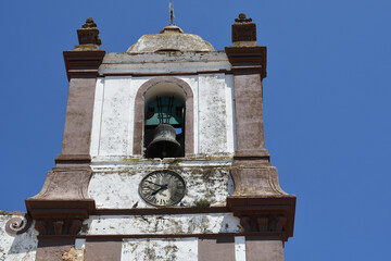 Old bell tower with a clock, under a clear blue sky