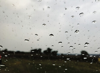 Rain Drops on Window with Blurry Landscape Background.