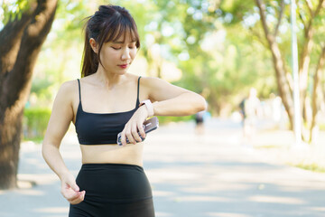 Asian woman using smartwatch or tracker to track her workout progress.