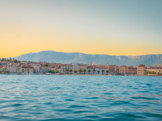 Sunset over Split, Croatia, with historic waterfront buildings and distant mountains reflected in...