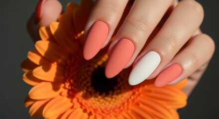 Hand with coral nails holding orange flower