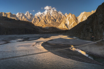 Suspension Bridge over River with Karakoram Mountains at Sunset, Pakistan