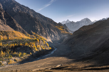 Autumn Forest and River Valley Beneath Snowy Peaks in Hunza, Pakistan