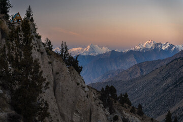 Sunset View of Remote Cabin on Mountain Ridge Overlooking Snowy Peaks