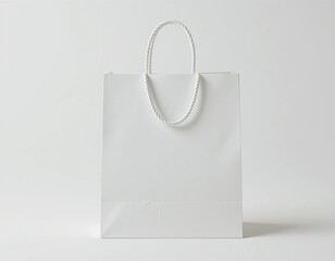 A plain white shopping bag with rope handles standing upright on a spotless white background.