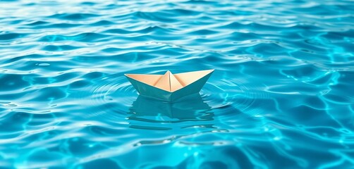 Fototapeta premium Tiny origami paper boat floats gently on rippling blue seawater, shadow, origami
