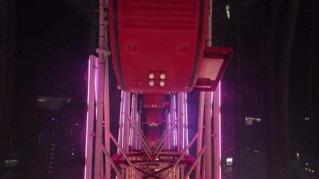 A vibrant view of a Ferris wheel at night, showcasing bright, colorful lights illuminating its structure against the dark sky. A captivating sight that highlights the fun and excitement of carnival ri