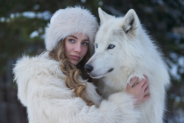 The woman wears a fluffy white fur coat and a matching white fur hat, with wavy blonde hair cascading down one side. 