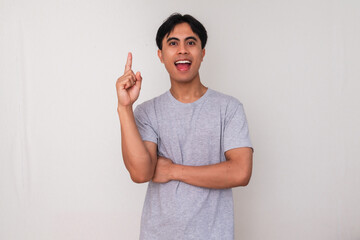 Excited young Asian man pointing up with inspired expression as if getting a new idea, isolated on...