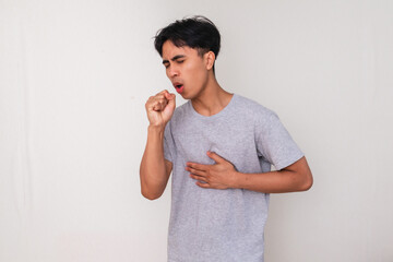 Unhealthy young Asian man coughing with hand covering mouth on white background