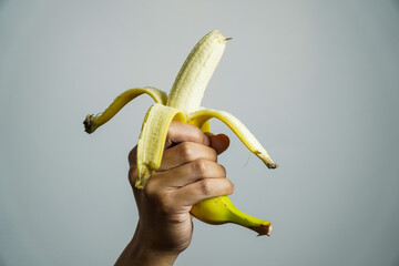 hand holding a partially peeled banana, ready to eat.