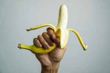 hand holding a partially peeled banana, ready to eat.