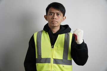 Energetic young Asian man in a safety vest and gloves, shouting and raising his fist in a gesture...