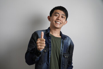 A young Asian man gives a clear thumbs-up gesture