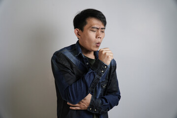 Asian Man Coughing into His Fist with Closed Eyes