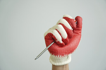 Hand wearing a red and white work glove firmly grips a screwdriver, ready for repair or...