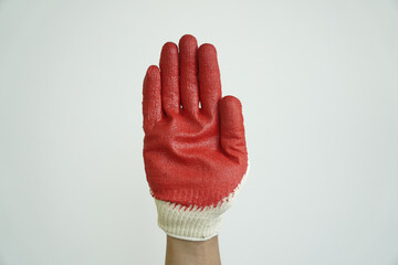 Hand in a red and white work glove held up with palm facing forward, signaling stop, warning, or refusal.