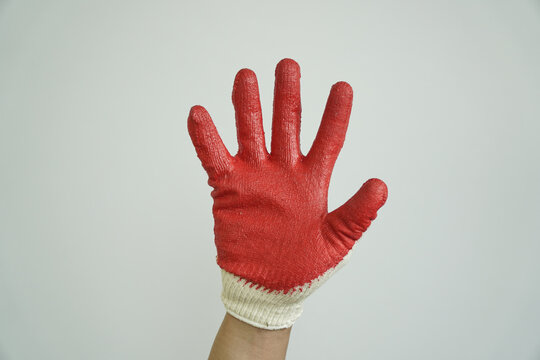 Hand in a red and white work glove held up with palm facing forward, signaling stop, warning, or refusal.