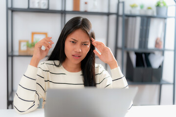 Young asian woman feeling frustrated and overwhelmed while working remotely, sitting at desk in...