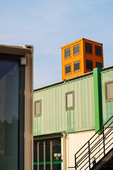 Exterior view of a contemporary building complex constructed from stacked, colorful shipping containers, showcasing innovative upcycled architecture