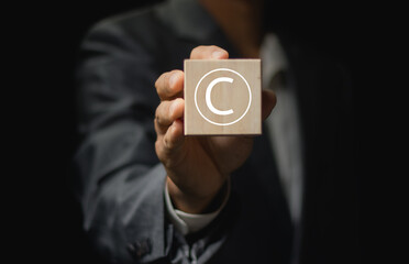 Person holding wooden block with copyright icon for author rights and patented intellectual...