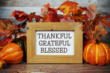 Thankful, Grateful, Blessed text with maple leaf decoration on wooden background