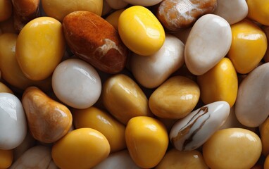 Close-up of colorful smooth polished natural stones in yellow white brown shades, arranged together on a flat surface for decorative or jewelry crafting purposes