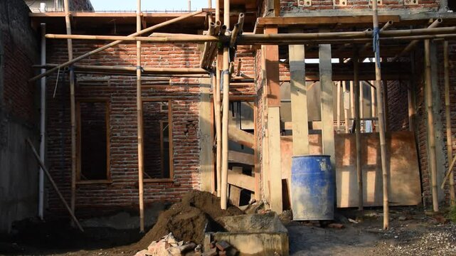 Unfinished house buildings in Indonesia with exposed bricks and construction materials