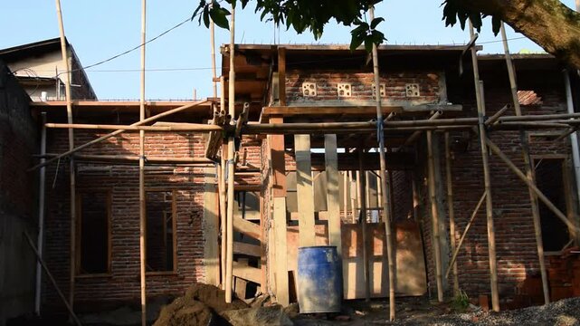 Unfinished house buildings in Indonesia with exposed bricks and construction materials