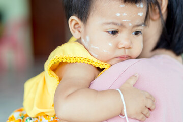 mother holding baby with thanaka paste, portrait baby girl in her mother arms, thai asia kid, baby, child, asian family lifestyle