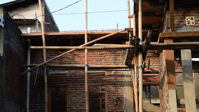 Unfinished house buildings in Indonesia with exposed bricks and construction materials