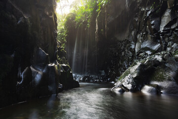 Visit the charm of Indonesia with the Lorong Watu waterfall, North Bengkulu. A narrow alley lined with stone walls, the morning light shines on the waterfall