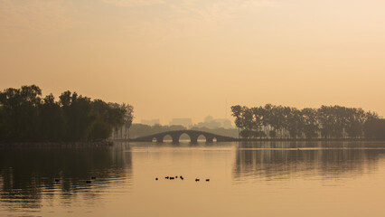 The lake and arched bridge of Beijing's Yuyuantan Park shrouded in morning mist.

