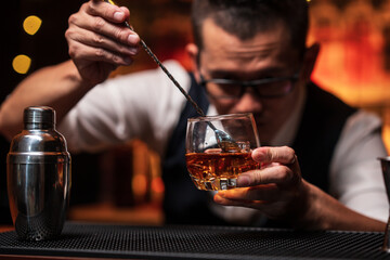 Bartender is pouring whiskey into a glass a customer's glass.