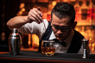 Bartender is pouring whiskey into a glass a customer's glass.	
