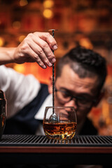 Bartender is pouring whiskey into a glass a customer's glass.	
