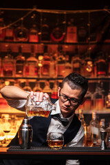 Bartender is pouring whiskey into a glass a customer's glass.	