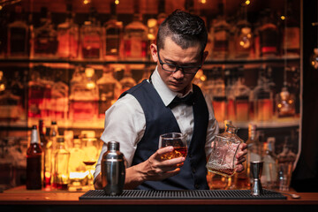 Bartender is pouring whiskey into a glass a customer's glass.