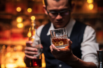 Bartender is pouring whiskey into a glass a customer's glass.	