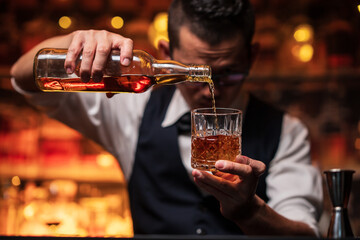 Bartender is pouring whiskey into a glass a customer's glass.	
