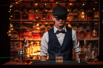 Bartender is pouring whiskey into a glass a customer's glass.	