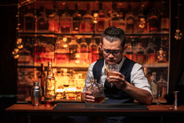 Bartender is pouring whiskey into a glass a customer's glass.	
