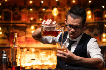 Bartender is pouring whiskey into a glass a customer's glass.	
