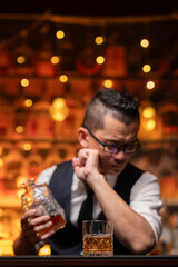Bartender is pouring whiskey into a glass a customer's glass.
