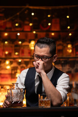 Bartender is pouring whiskey into a glass a customer's glass.