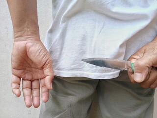 A man holds a hidden knife gleaming behind his back. Illustration of criminal activity.
