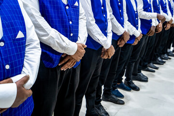 Group of men in blue vests standing together. group of people holding hands. Large group of waiters...