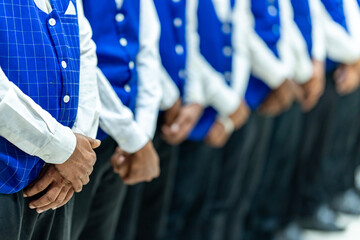 Group of men in blue vests standing together. group of people holding hands. Large group of waiters...