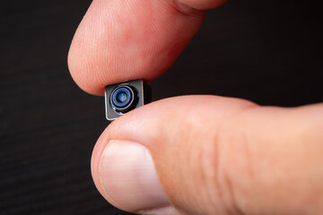 Miniature camera with tiny lens in hand, showcasing its intricate details and technology.